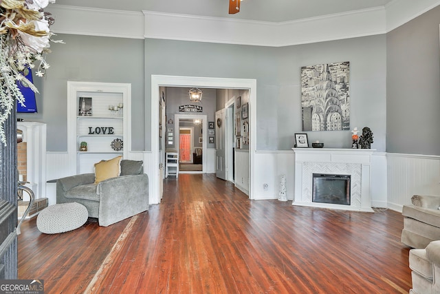 living room with wood-type flooring, a fireplace, crown molding, and built in features