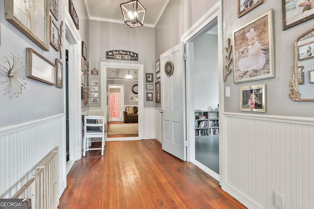 corridor featuring a chandelier, dark wood-type flooring, and crown molding