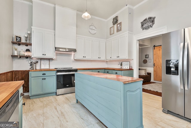 kitchen with a high ceiling, appliances with stainless steel finishes, and wood counters