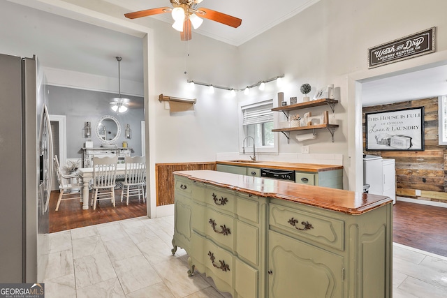 kitchen featuring wooden counters, wooden walls, sink, stainless steel fridge with ice dispenser, and green cabinets