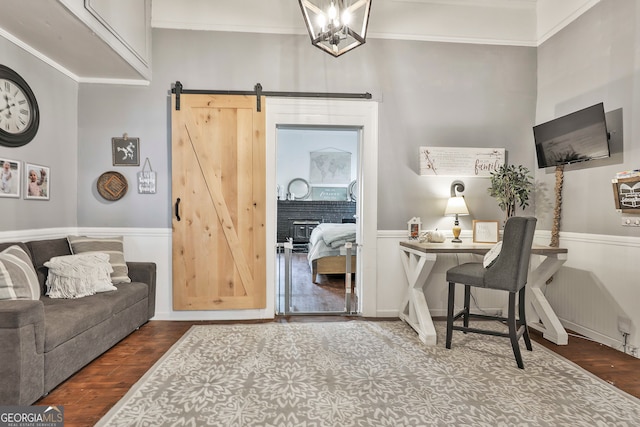 office area with wood-type flooring, a barn door, ornamental molding, and a chandelier