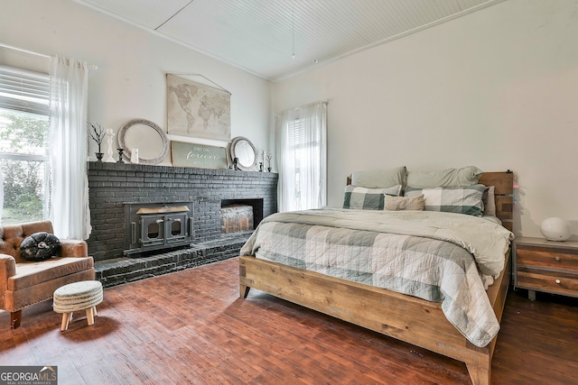 bedroom featuring wood-type flooring, crown molding, and a wood stove