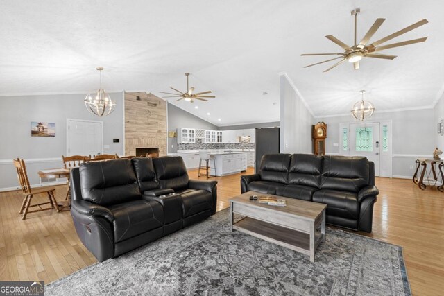 living room featuring ornamental molding, light wood-type flooring, plenty of natural light, and lofted ceiling