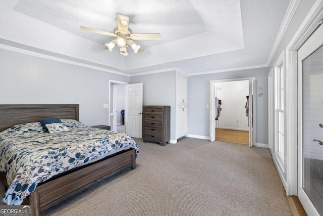 bedroom featuring carpet flooring, a textured ceiling, a tray ceiling, and ceiling fan