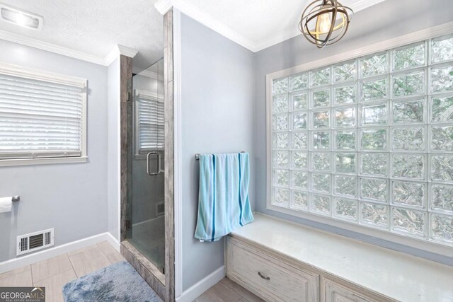 bathroom featuring a shower with door, tile patterned flooring, a textured ceiling, and ornamental molding