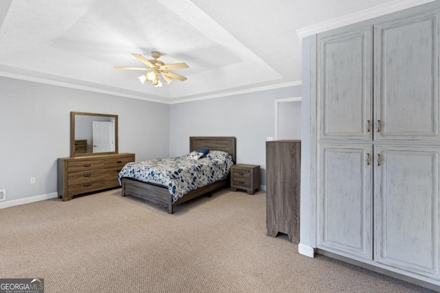 carpeted bedroom with ceiling fan, a raised ceiling, and crown molding