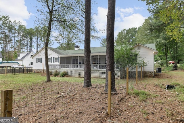 back of property with a lawn and a sunroom