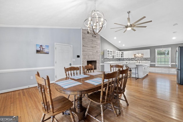 1011 Sugar Hill Way, Buckhead, GA 30625 - dining space with ornamental molding, lofted ceiling, a fireplace, light wood-type flooring, and ceiling fan with notable chandelier