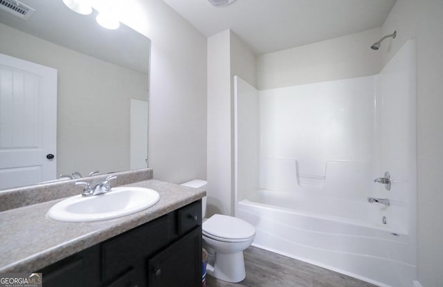 full bathroom with vanity, hardwood / wood-style floors, washtub / shower combination, and toilet