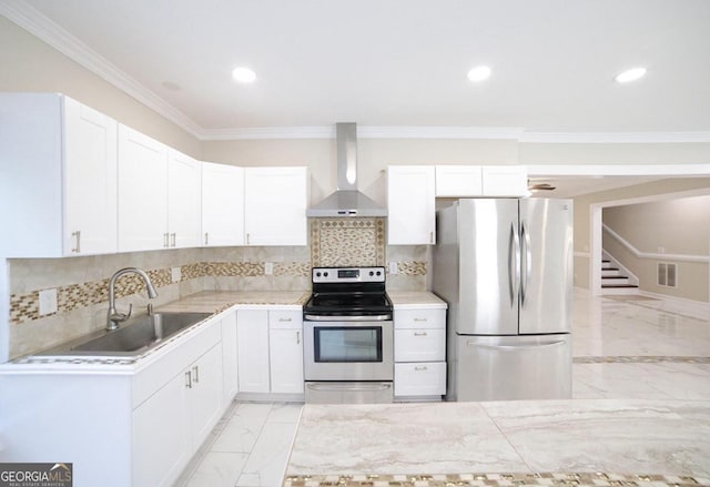 kitchen with ornamental molding, sink, wall chimney range hood, white cabinetry, and appliances with stainless steel finishes