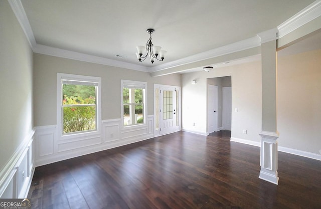 empty room featuring ornamental molding, a chandelier, dark wood-type flooring, and ornate columns