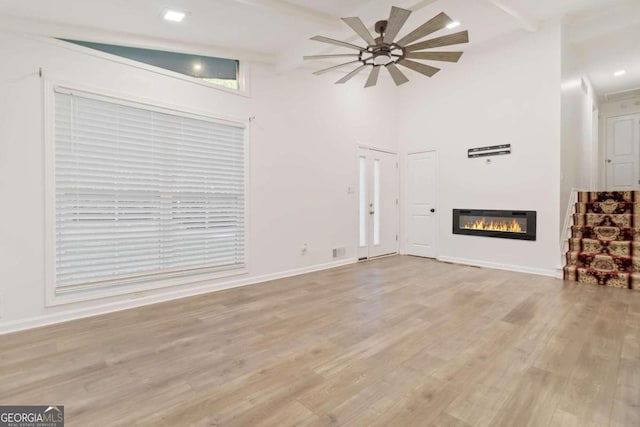 unfurnished living room with ceiling fan, light hardwood / wood-style flooring, and lofted ceiling with beams