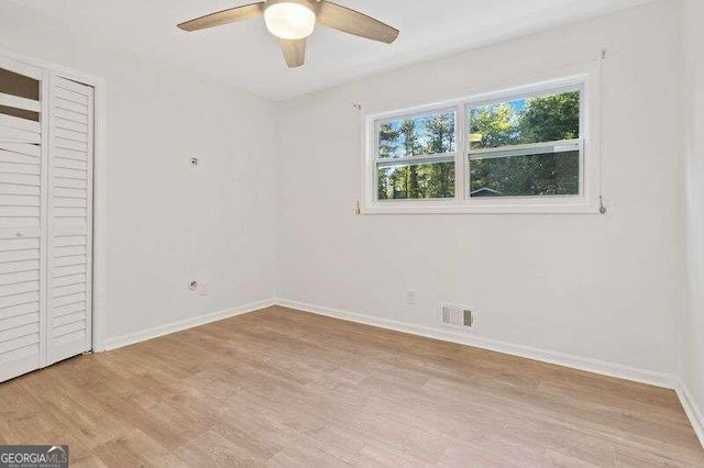 unfurnished bedroom featuring light hardwood / wood-style flooring, ceiling fan, and a closet