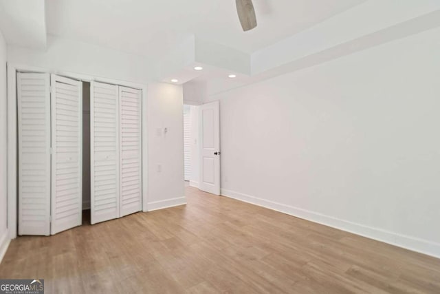 unfurnished bedroom with light wood-type flooring, ceiling fan, and a closet