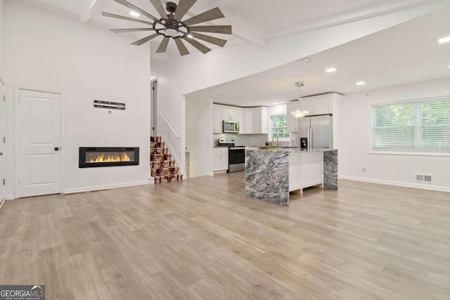 kitchen with stainless steel appliances, white cabinets, light hardwood / wood-style floors, and hanging light fixtures