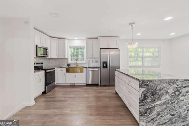 kitchen featuring appliances with stainless steel finishes, hardwood / wood-style flooring, sink, and white cabinets