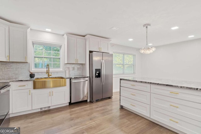 kitchen with appliances with stainless steel finishes, plenty of natural light, sink, and white cabinetry