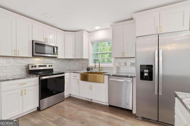 kitchen featuring appliances with stainless steel finishes, light hardwood / wood-style floors, white cabinetry, and sink