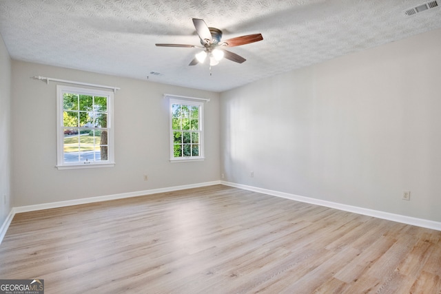 unfurnished room with ceiling fan, a textured ceiling, and light wood-type flooring