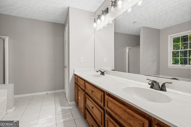 bathroom featuring tile patterned floors, vanity, a shower with shower door, and a textured ceiling