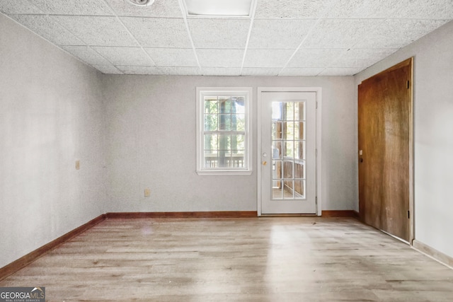 spare room with a drop ceiling and light hardwood / wood-style floors