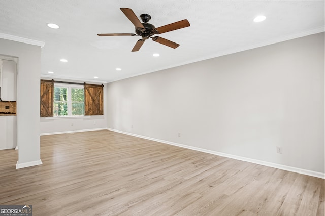 unfurnished living room featuring ceiling fan, light hardwood / wood-style flooring, crown molding, and a barn door