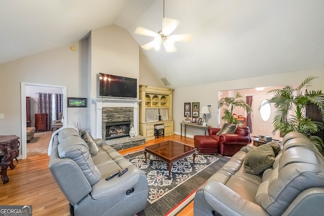 living room with a stone fireplace, high vaulted ceiling, hardwood / wood-style floors, and ceiling fan