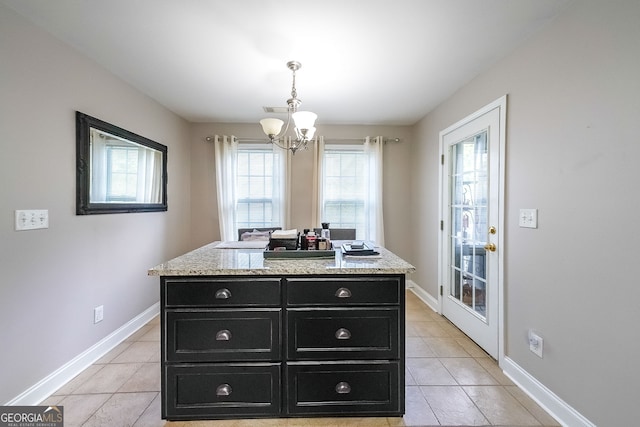 kitchen featuring light stone countertops, hanging light fixtures, light tile patterned floors, and a center island