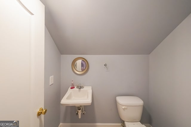 bathroom with vaulted ceiling, sink, and toilet