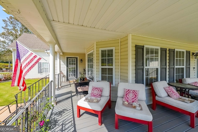 wooden terrace with an outdoor hangout area and a lawn