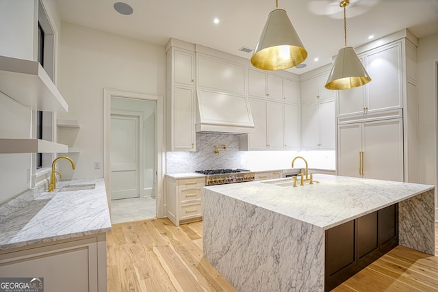 kitchen with white cabinets, light wood-type flooring, sink, and light stone countertops