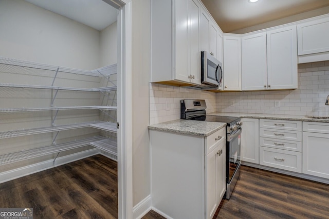 kitchen with white cabinetry, sink, dark wood-type flooring, decorative backsplash, and appliances with stainless steel finishes