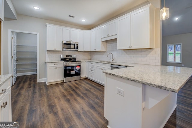 kitchen featuring kitchen peninsula, white cabinetry, decorative light fixtures, and appliances with stainless steel finishes