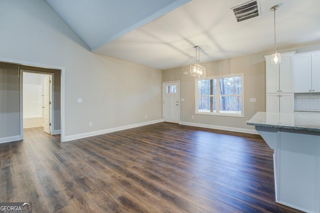 unfurnished living room with a notable chandelier, dark hardwood / wood-style flooring, and lofted ceiling