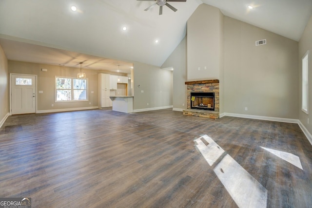 unfurnished living room with a stone fireplace, ceiling fan, high vaulted ceiling, and dark hardwood / wood-style floors