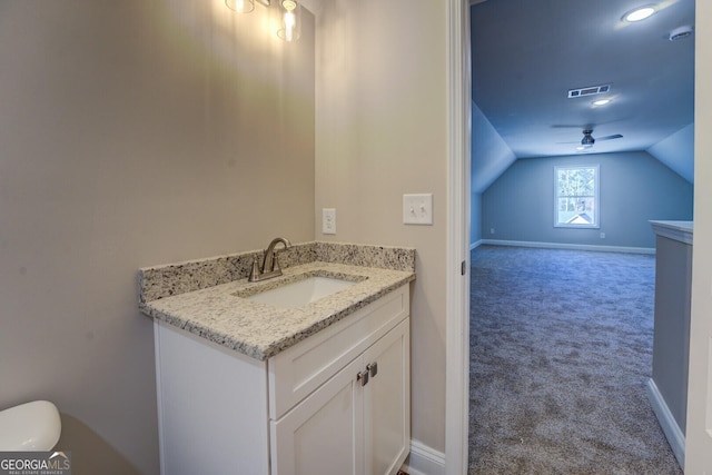 bathroom featuring ceiling fan, toilet, vanity, and vaulted ceiling