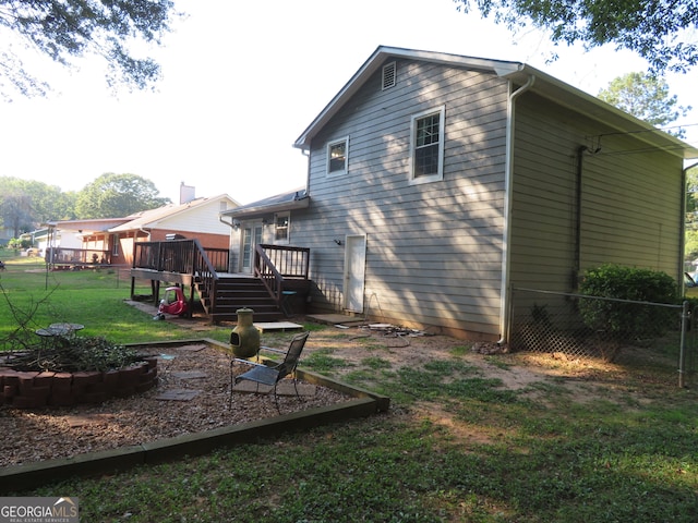 rear view of house with a lawn and a deck