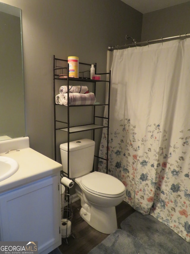 bathroom with a shower with shower curtain, hardwood / wood-style flooring, vanity, and toilet