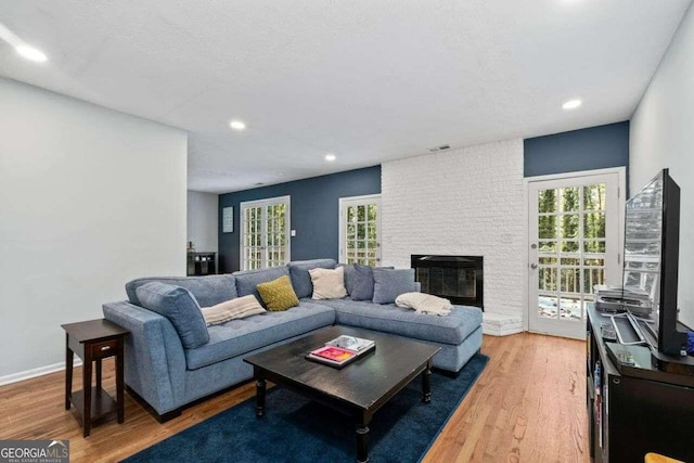 living room featuring a brick fireplace, hardwood / wood-style floors, and a healthy amount of sunlight