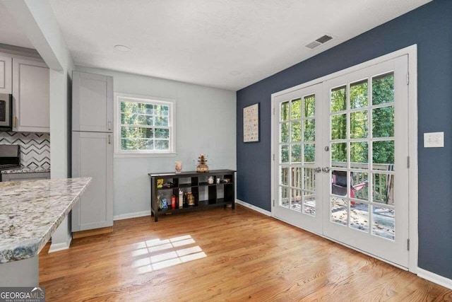 entryway with french doors, light hardwood / wood-style flooring, and a healthy amount of sunlight