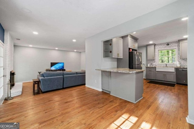 kitchen with gray cabinets, light hardwood / wood-style floors, sink, kitchen peninsula, and appliances with stainless steel finishes