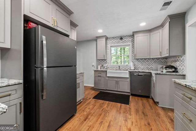 kitchen featuring light hardwood / wood-style floors, tasteful backsplash, gray cabinets, stainless steel appliances, and sink