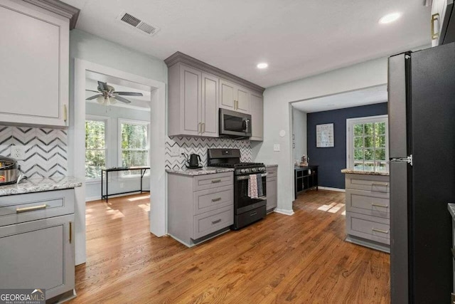 kitchen featuring gray cabinetry, light wood-type flooring, appliances with stainless steel finishes, and a healthy amount of sunlight