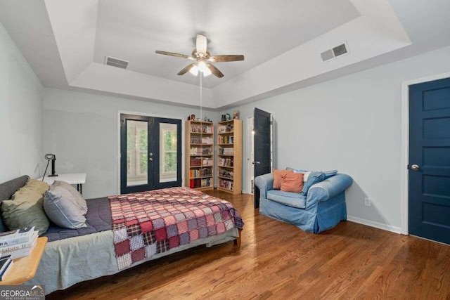 bedroom with wood-type flooring, a tray ceiling, and ceiling fan