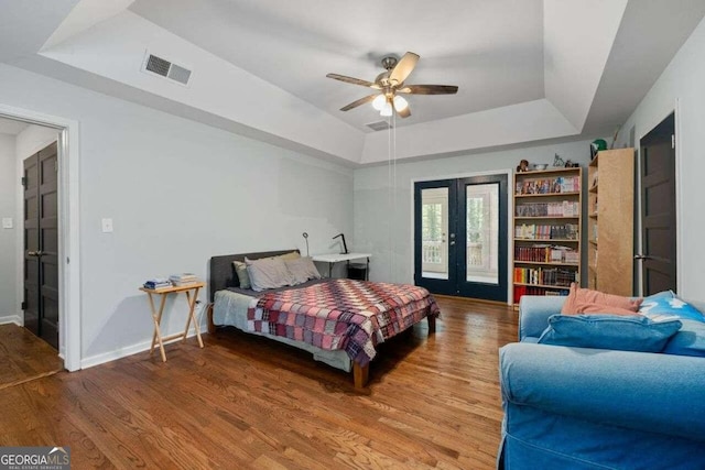 bedroom featuring a raised ceiling, access to exterior, ceiling fan, french doors, and hardwood / wood-style flooring