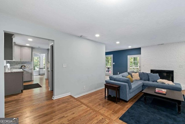 living room with a stone fireplace, plenty of natural light, and hardwood / wood-style floors