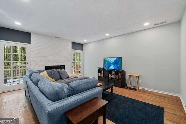 living room with a textured ceiling, a fireplace, and hardwood / wood-style floors