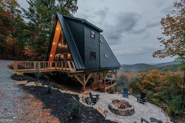 rear view of house featuring an outdoor fire pit, a deck with mountain view, and a patio area