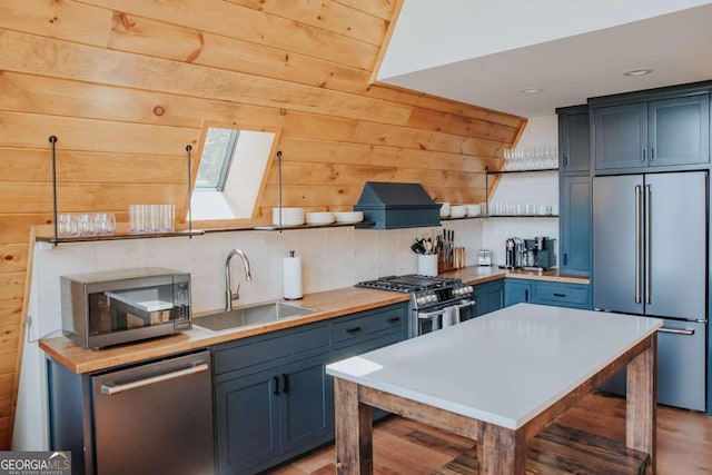 kitchen featuring blue cabinets, light wood-type flooring, high quality appliances, sink, and custom exhaust hood