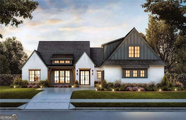 modern inspired farmhouse featuring board and batten siding, a yard, french doors, and roof with shingles